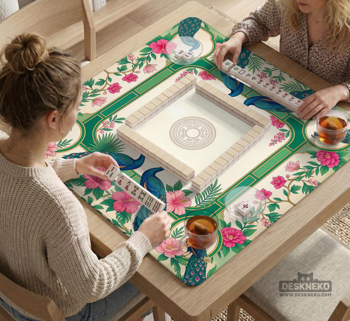 Green mahjong mat with peacocks, hibiscus flowers, tropical leaves, cream center space, and a scalloped floral border.