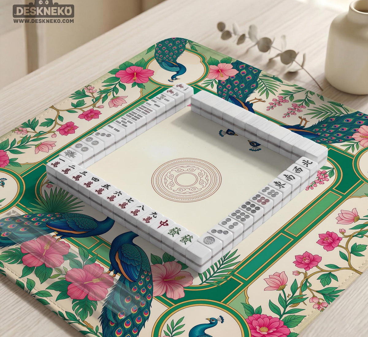 Green mahjong mat with peacocks, hibiscus flowers, tropical leaves, cream center space, and a scalloped floral border.