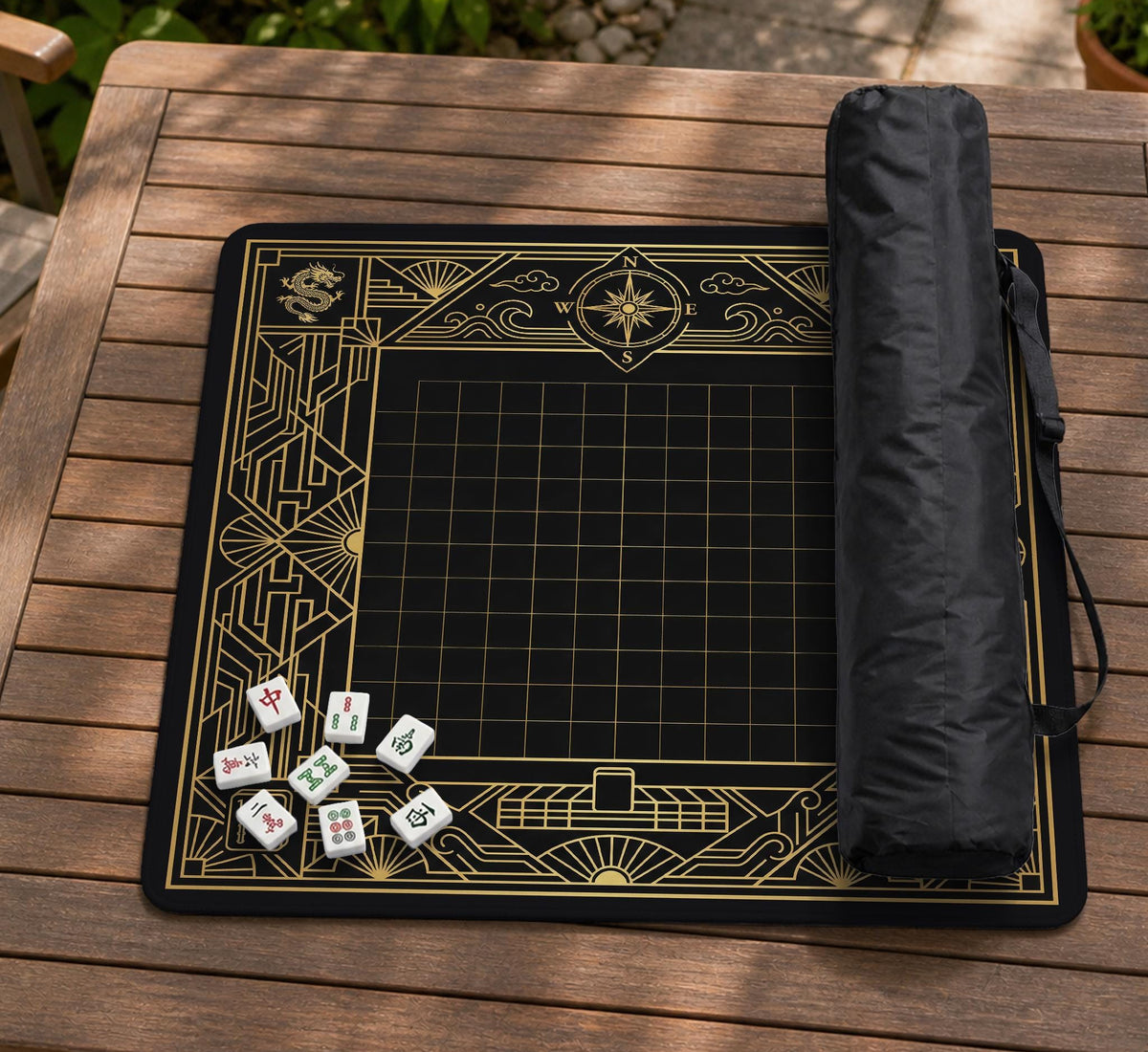 Black and gold square mahjong mat with a scalloped edge, geometric border, thin line details, fan motifs, and dragon and phoenix accents around an open center.
