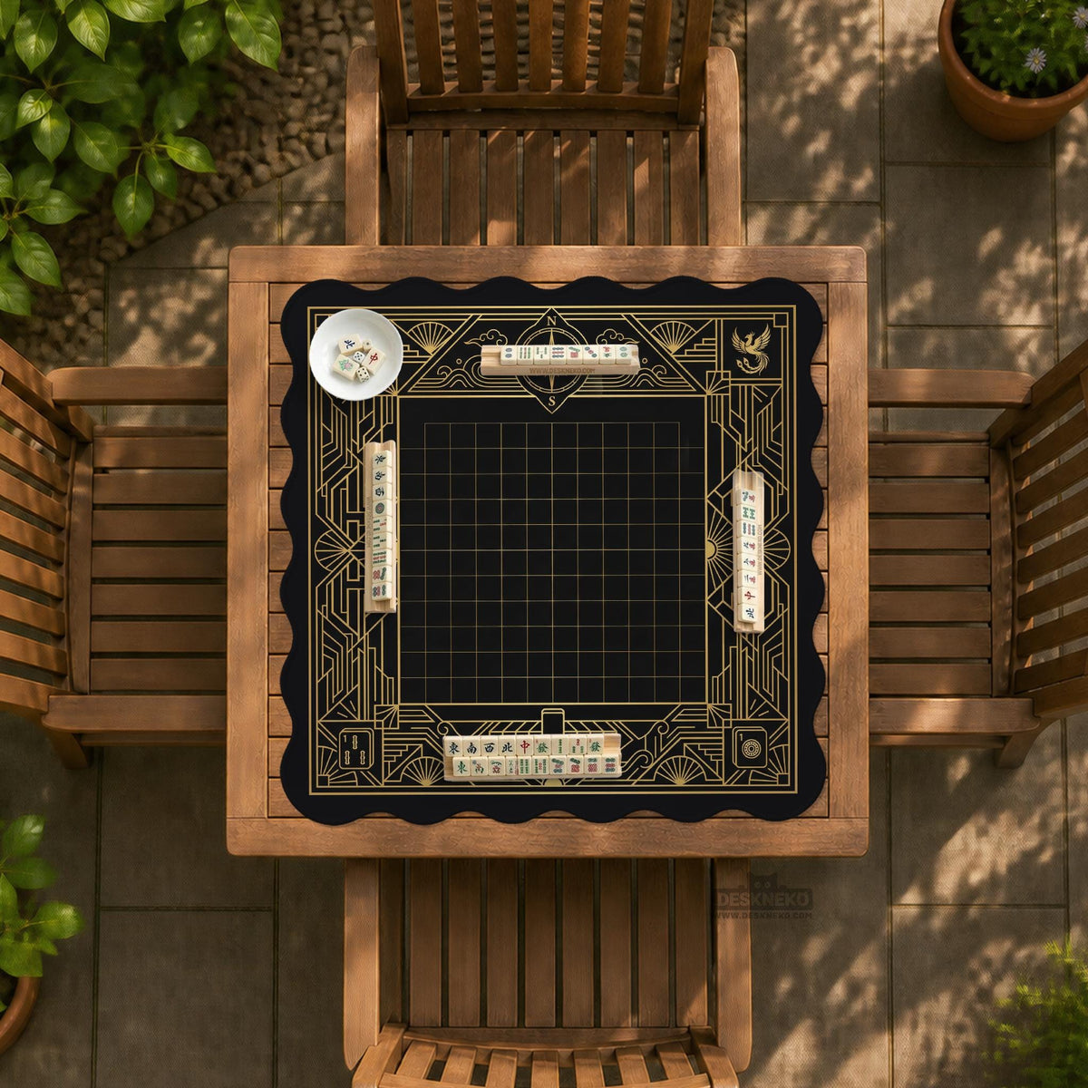 Black and gold square mahjong mat with a scalloped edge, geometric border, thin line details, fan motifs, and dragon and phoenix accents around an open center.