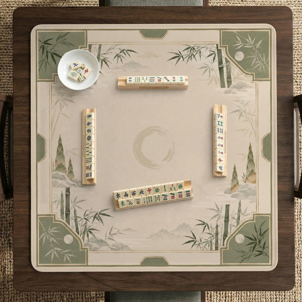 Square mahjong mat with a sage green bamboo and mountain design, cream center, scalloped border details, and gold line accents.