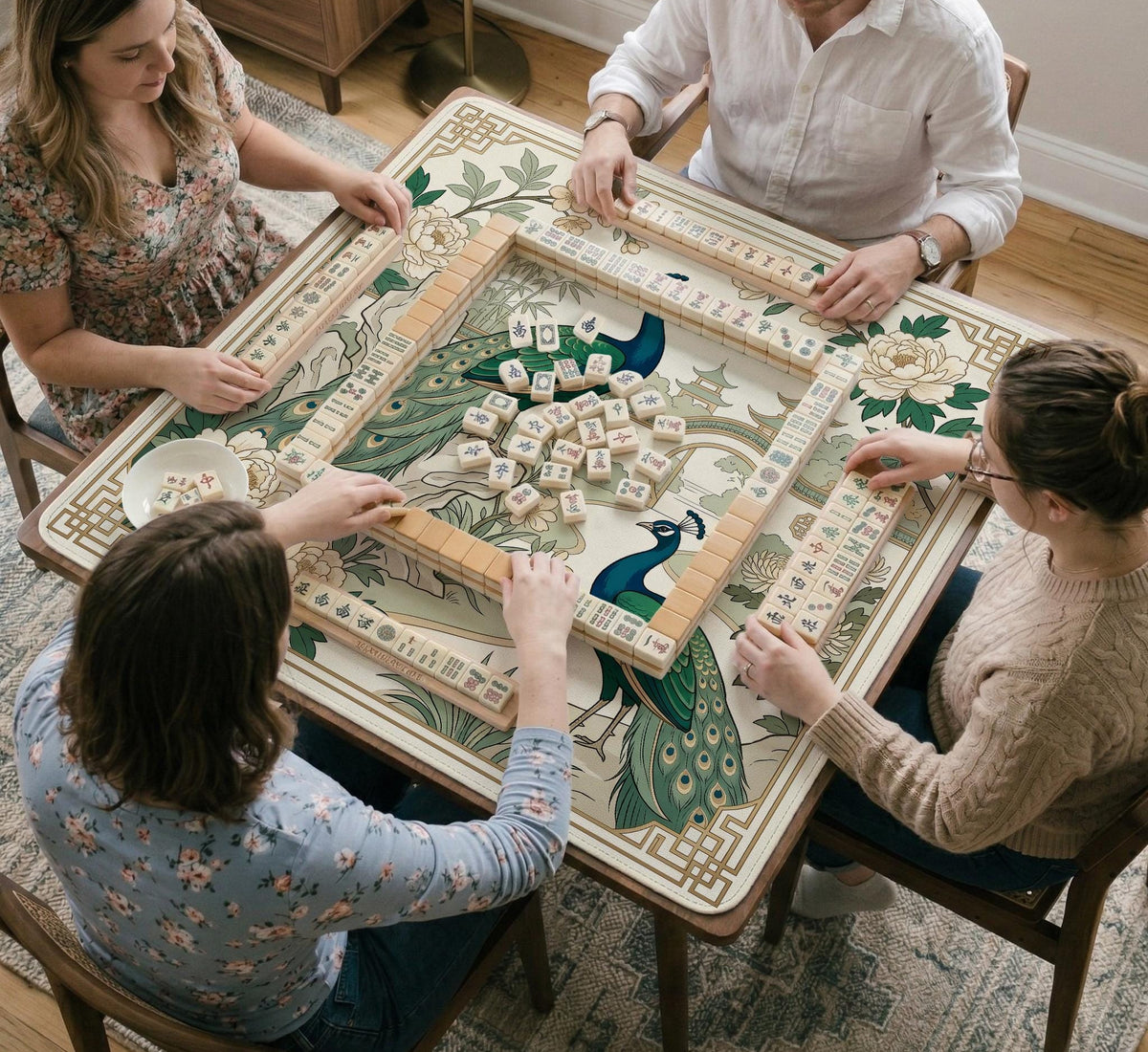 A green mahjong mat with peacock, floral, bamboo, pagoda, and gold border artwork in a scalloped chinoiserie style.