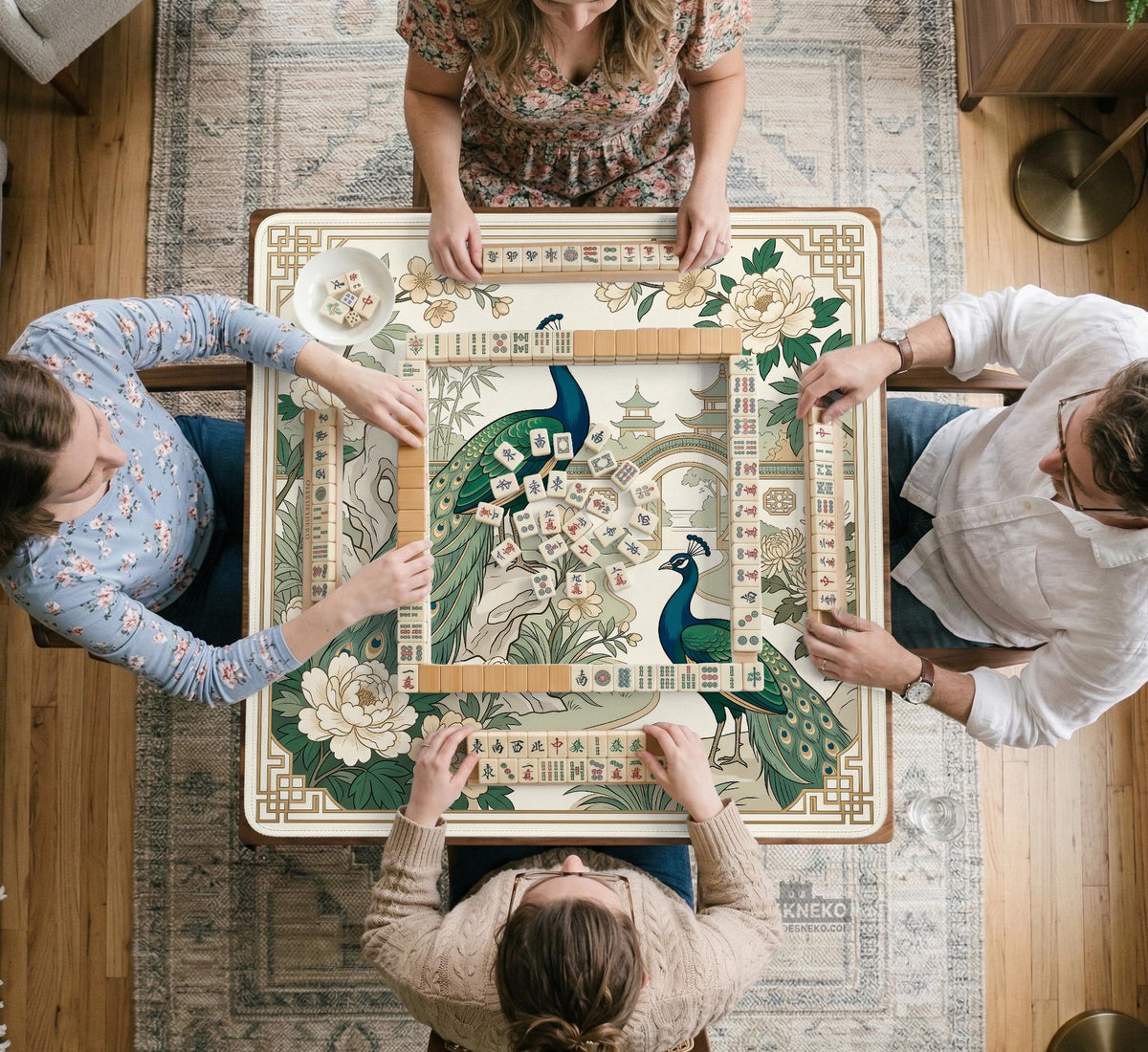 A green mahjong mat with peacock, floral, bamboo, pagoda, and gold border artwork in a scalloped chinoiserie style.