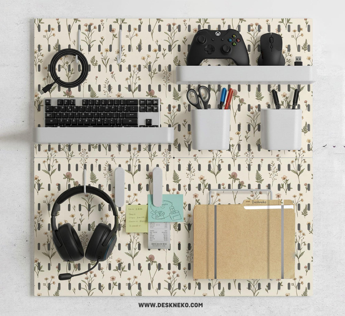 Cream pegboard wall organizer with small floral print, sage green stems, black slot layout, shelves, hooks, clips, and containers.