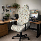 Cream chair cover with a scattered cottage garden floral print in red, blue, yellow, and green on a light background.
