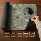 A desk mat with a repeating pattern of cats, leafy houseplants, cactus pots, and small plant-shop style details in sage green.