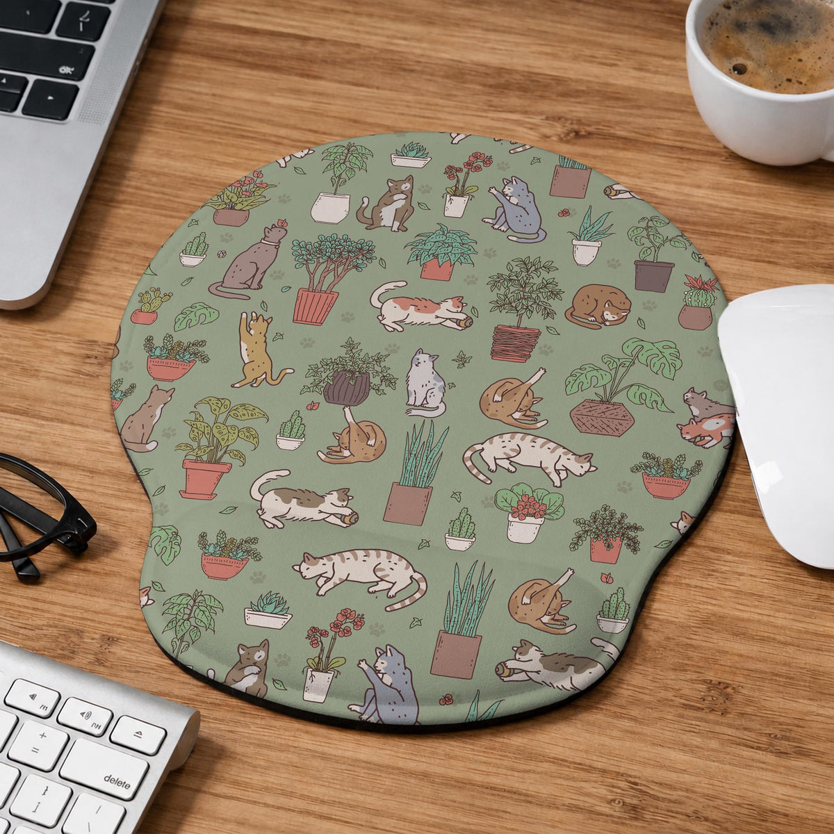 Sage green desk mat with a pattern of lounging cats, leafy plants, cactus pots, and earthy botanical details.