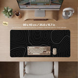 Black desk mat with a thin gray topographic contour line pattern.