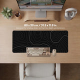 Black desk mat with a thin gray topographic contour line pattern.