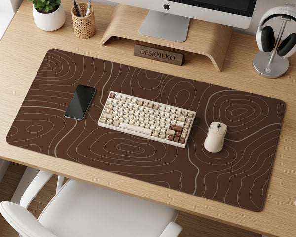 Brown desk mat with a repeating topographic contour line pattern in a neutral earth tone design.