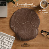Brown desk mat with a repeating topographic contour line pattern in a neutral earth tone design.