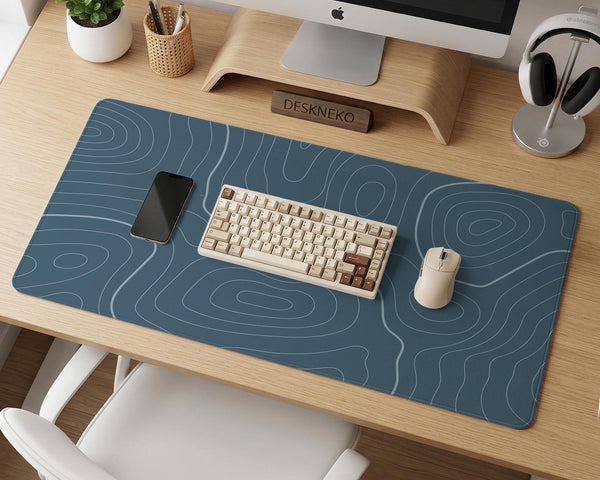 A slate blue desk mat with thin contour line map art on a light background.