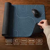 A slate blue desk mat with thin contour line map art on a light background.