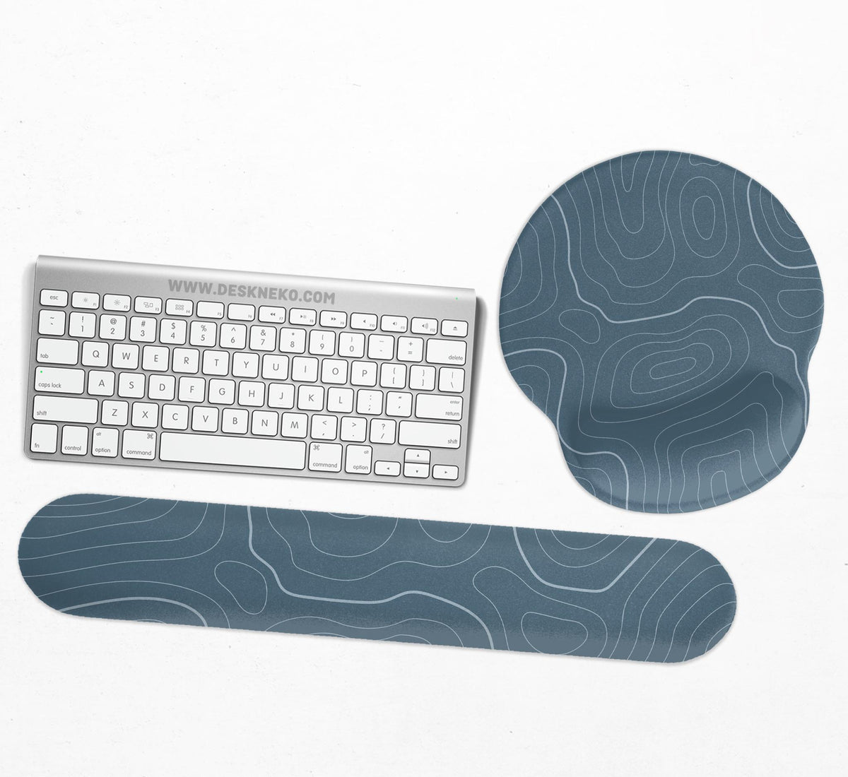 Muted blue desk mat with thin topographic line art pattern shown with matching mousepad and keyboard wrist rest options.