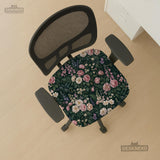 Green chair cover with a dark floral pattern, pink roses, cream flowers, and leafy botanical details on an office chair.