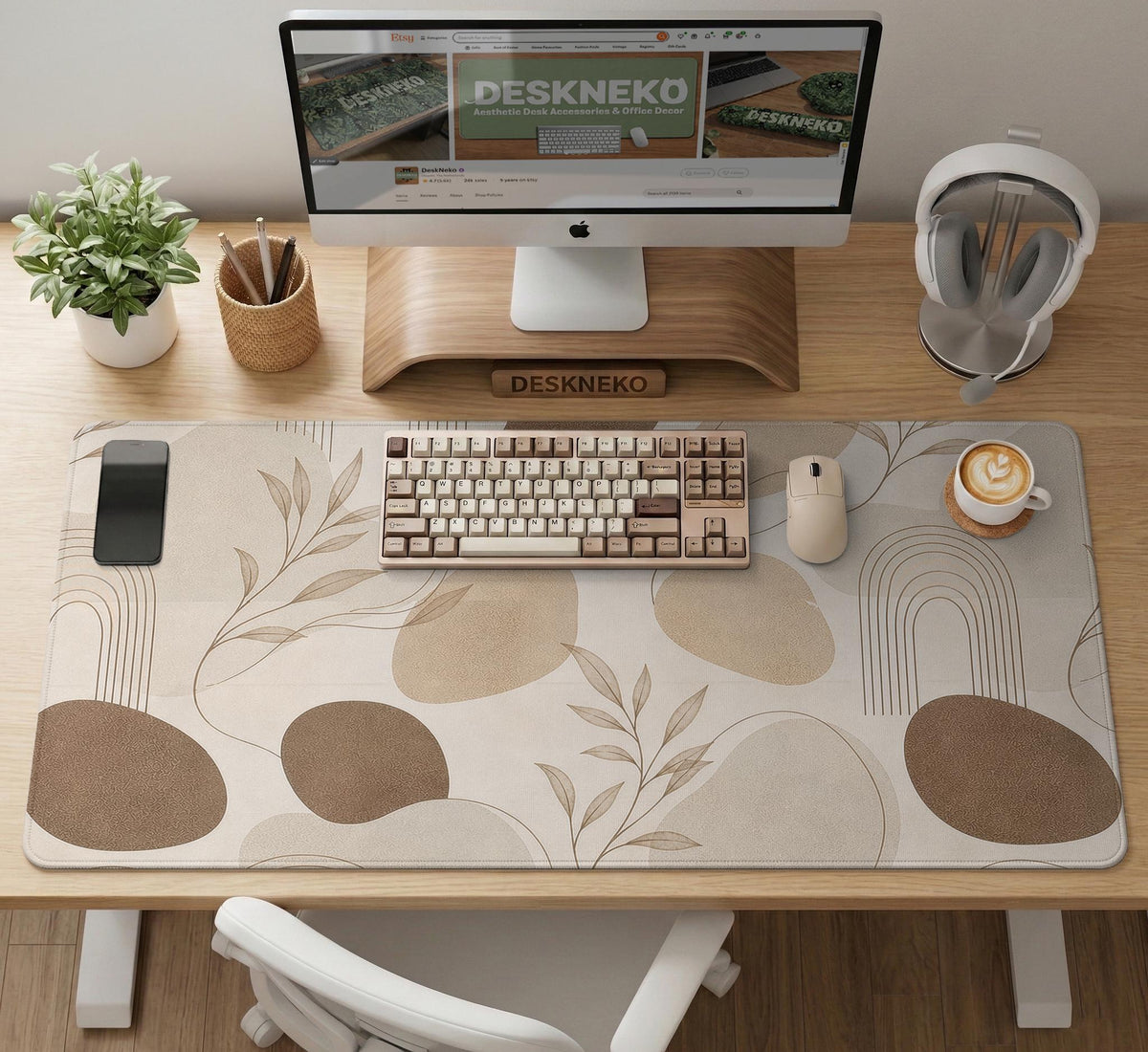 Beige desk mat with fine botanical line drawings and soft abstract shapes on a light neutral background.
