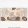 Beige desk mat with fine botanical line drawings and soft abstract shapes on a light neutral background.