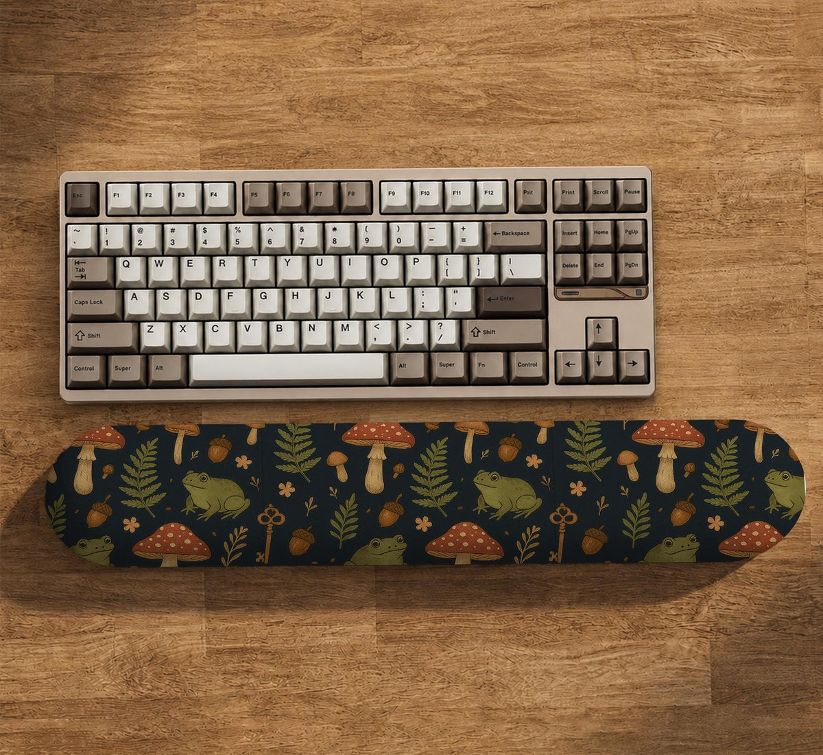 Dark botanical desk mat options with frogs, mushrooms, ferns, and acorns in brown and green tones, plus a matching keyboard wrist rest.