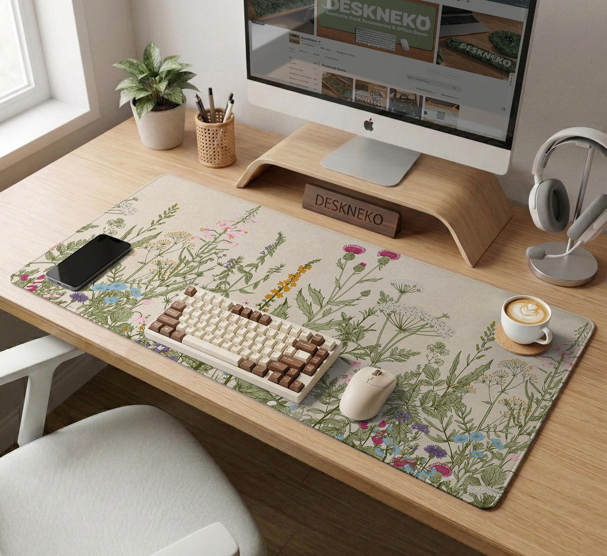 A desk mat with a botanical meadow design featuring wildflowers, leafy stems, and soft neutral colors.