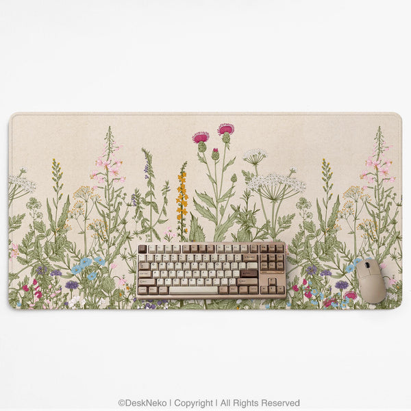 A desk mat with a botanical meadow design featuring wildflowers, leafy stems, and soft neutral colors.