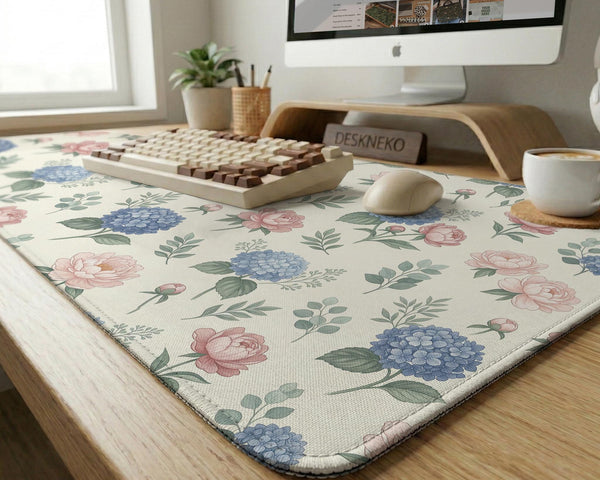 Floral desk mat with sage greenery, pink peonies, blue flowers, and a warm cream background.