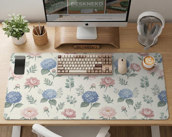 Floral desk mat with sage greenery, pink peonies, blue flowers, and a warm cream background.