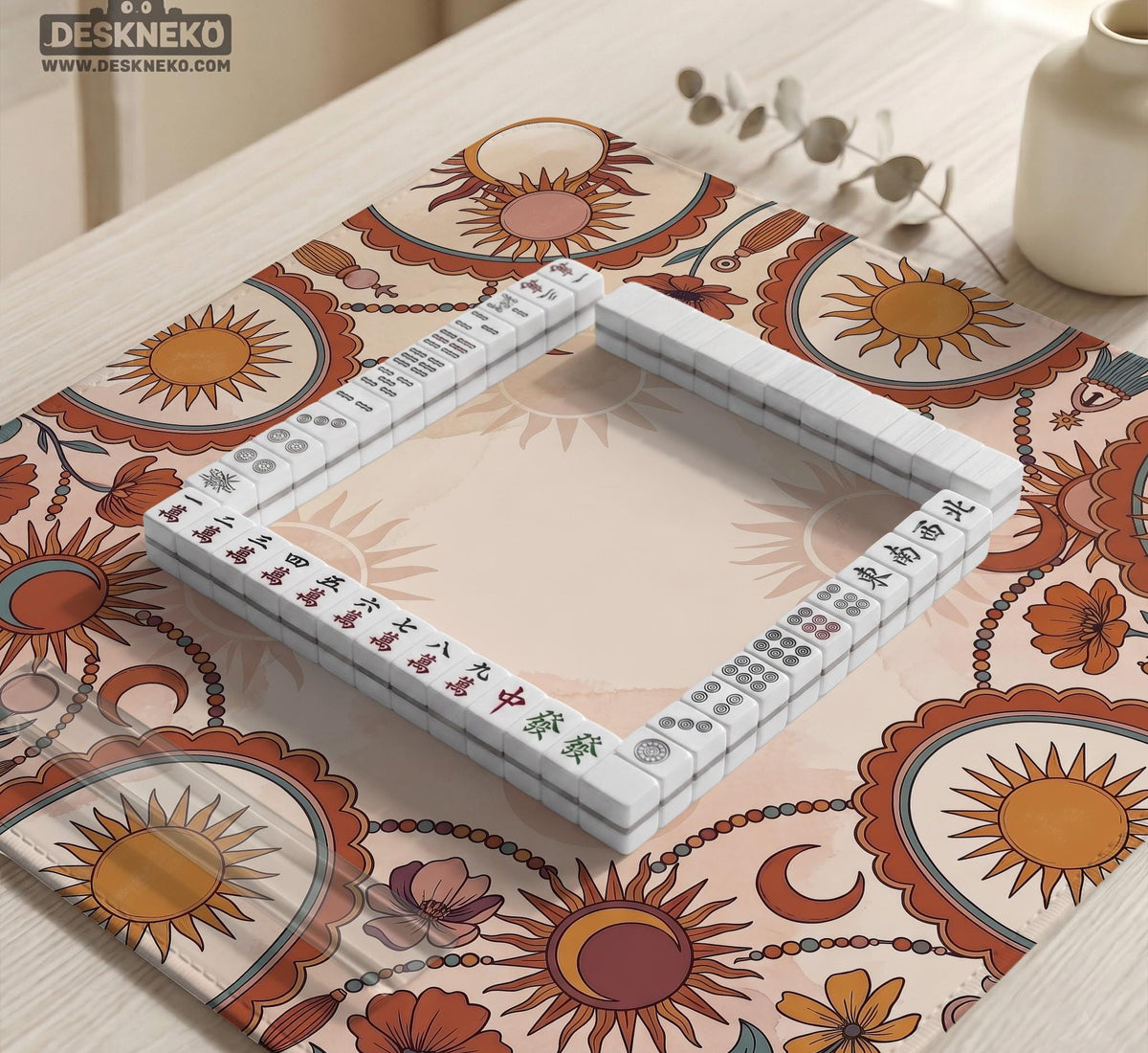 A square mahjong mat with a scalloped edge, sun and moon artwork, terracotta flowers, a soft cream background, and a decorative border around the play area.