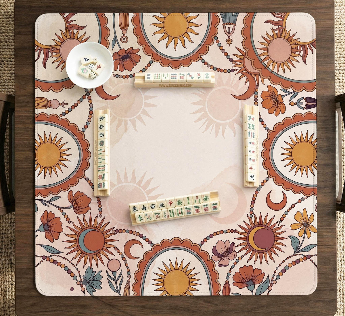 A square mahjong mat with a scalloped edge, sun and moon artwork, terracotta flowers, a soft cream background, and a decorative border around the play area.