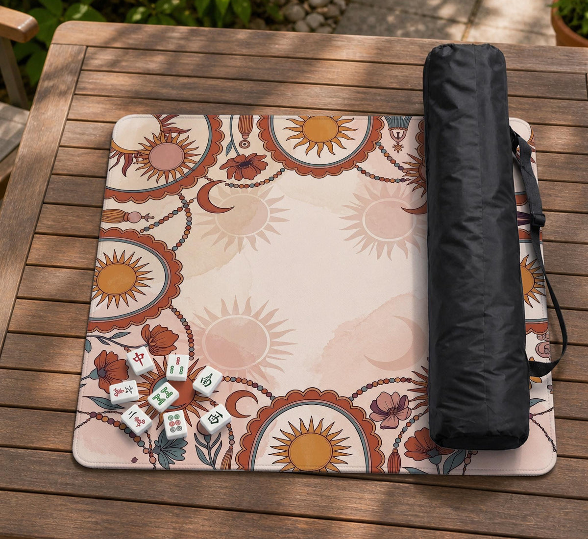 A square mahjong mat with a scalloped edge, sun and moon artwork, terracotta flowers, a soft cream background, and a decorative border around the play area.
