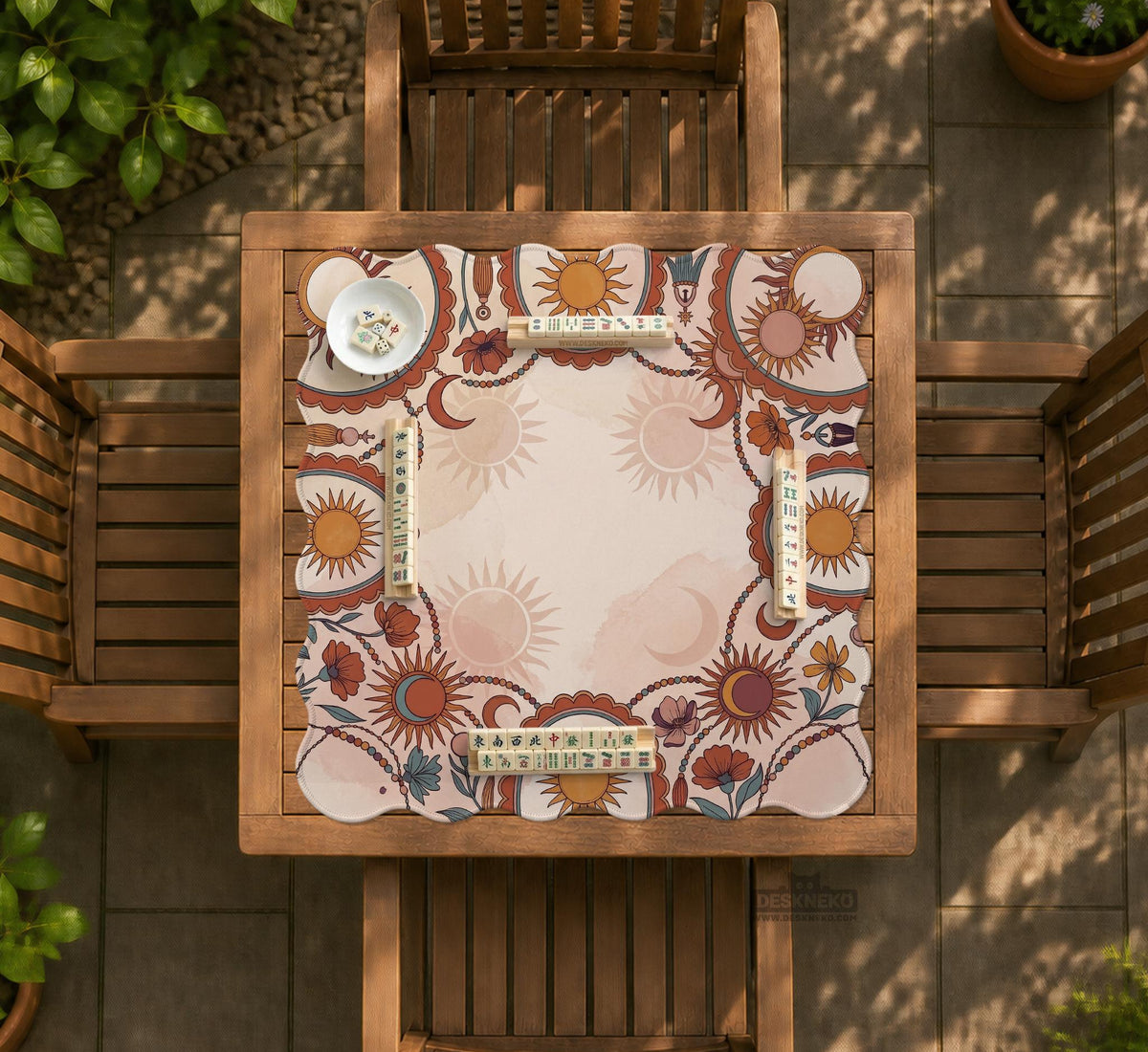 A square mahjong mat with a scalloped edge, sun and moon artwork, terracotta flowers, a soft cream background, and a decorative border around the play area.