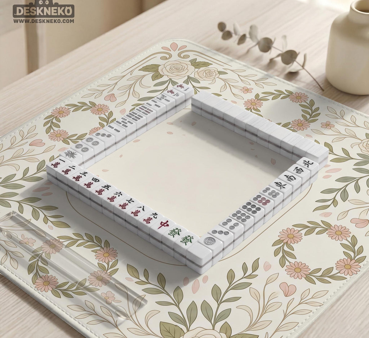 Square mahjong mat with a light floral border in sage green, cream, and blush around a plain center play area.