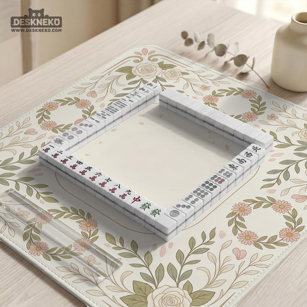 Square mahjong mat with a light floral border in sage green, cream, and blush around a plain center play area.
