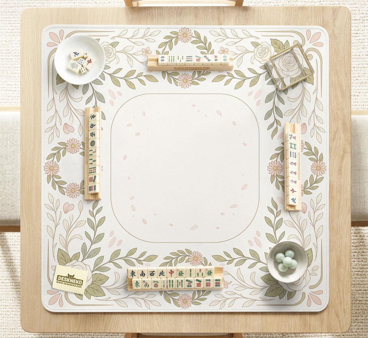 Square mahjong mat with a light floral border in sage green, cream, and blush around a plain center play area.