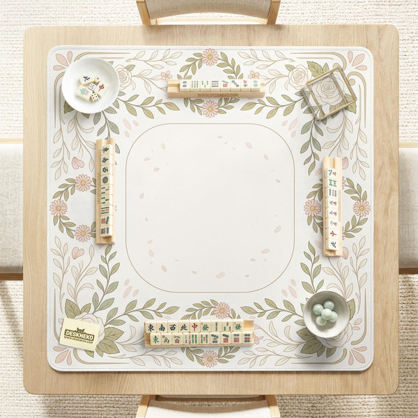 Square mahjong mat with a light floral border in sage green, cream, and blush around a plain center play area.
