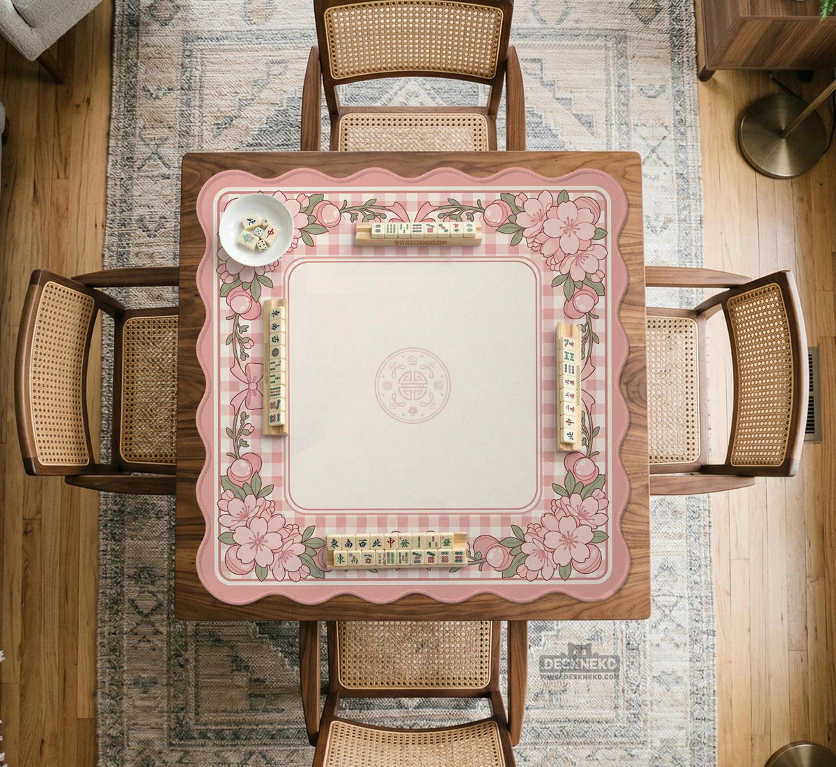 Pink gingham mahjong mat with a floral border, cherry blossom details, and a bow design around a plain center play area.