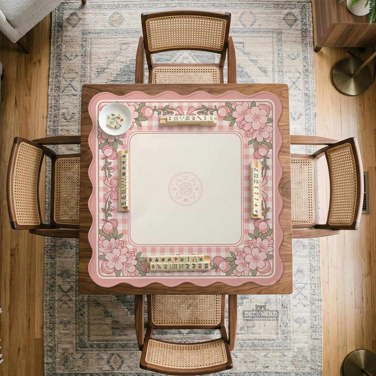 Square pink mahjong mat with a gingham border, floral corner details, and ribbon accents on a light background.