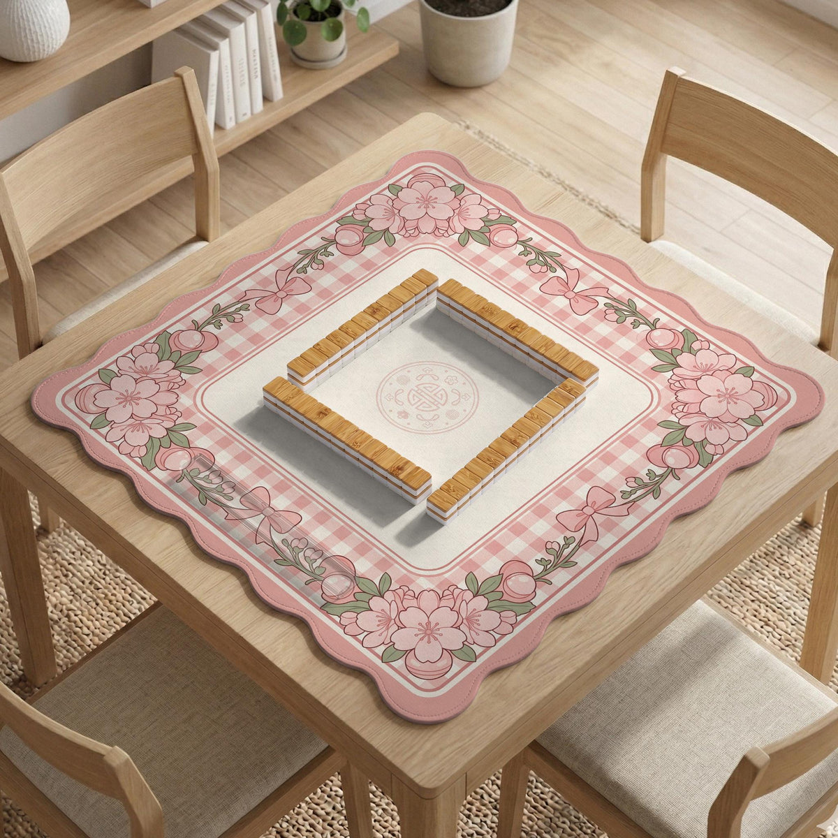 Square pink mahjong mat with a gingham border, floral corner details, and ribbon accents on a light background.