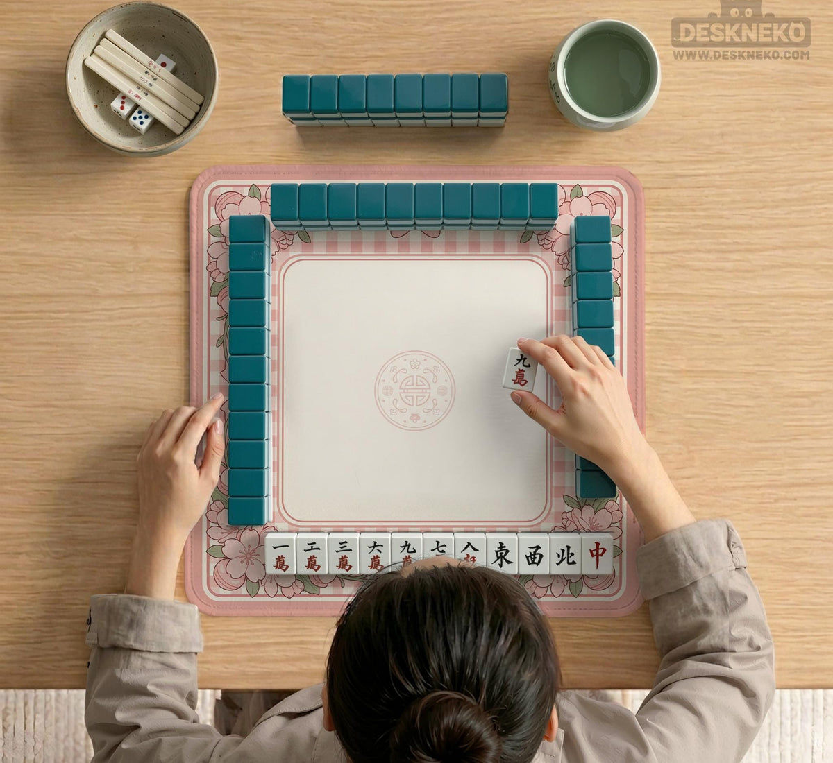 Pink gingham mahjong mat with a floral border, cherry blossom details, and a bow design around a plain center play area.