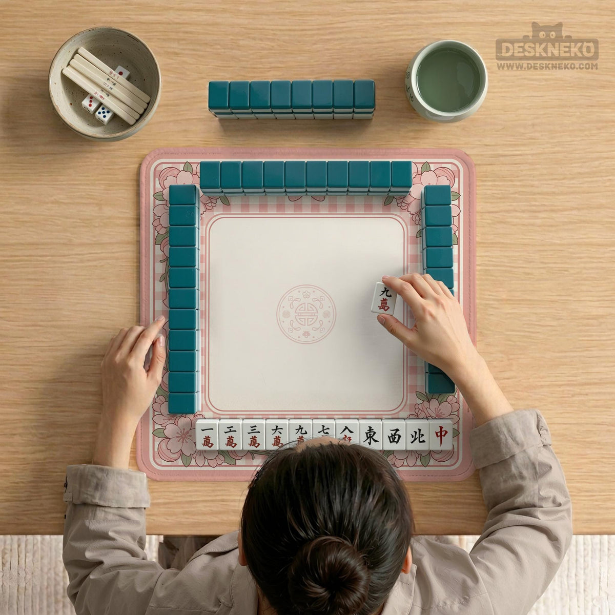 Pink gingham mahjong mat with a floral border, cherry blossom details, and a bow design around a plain center play area.