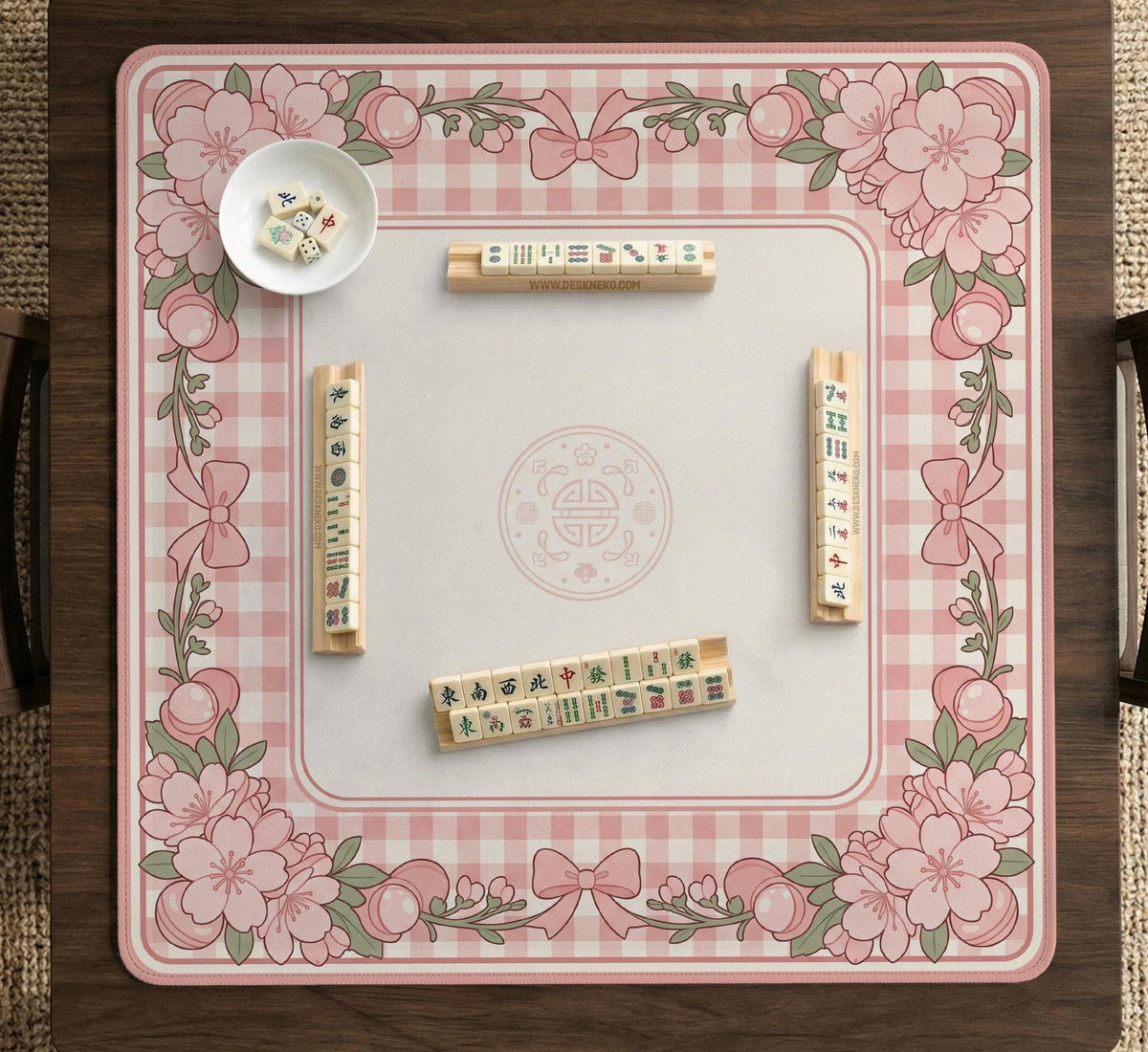 Pink gingham mahjong mat with a floral border, cherry blossom details, and a bow design around a plain center play area.