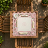 Square pink mahjong mat with a gingham border, floral corner details, and ribbon accents on a light background.