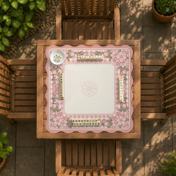 Square pink mahjong mat with a gingham border, floral corner details, and ribbon accents on a light background.