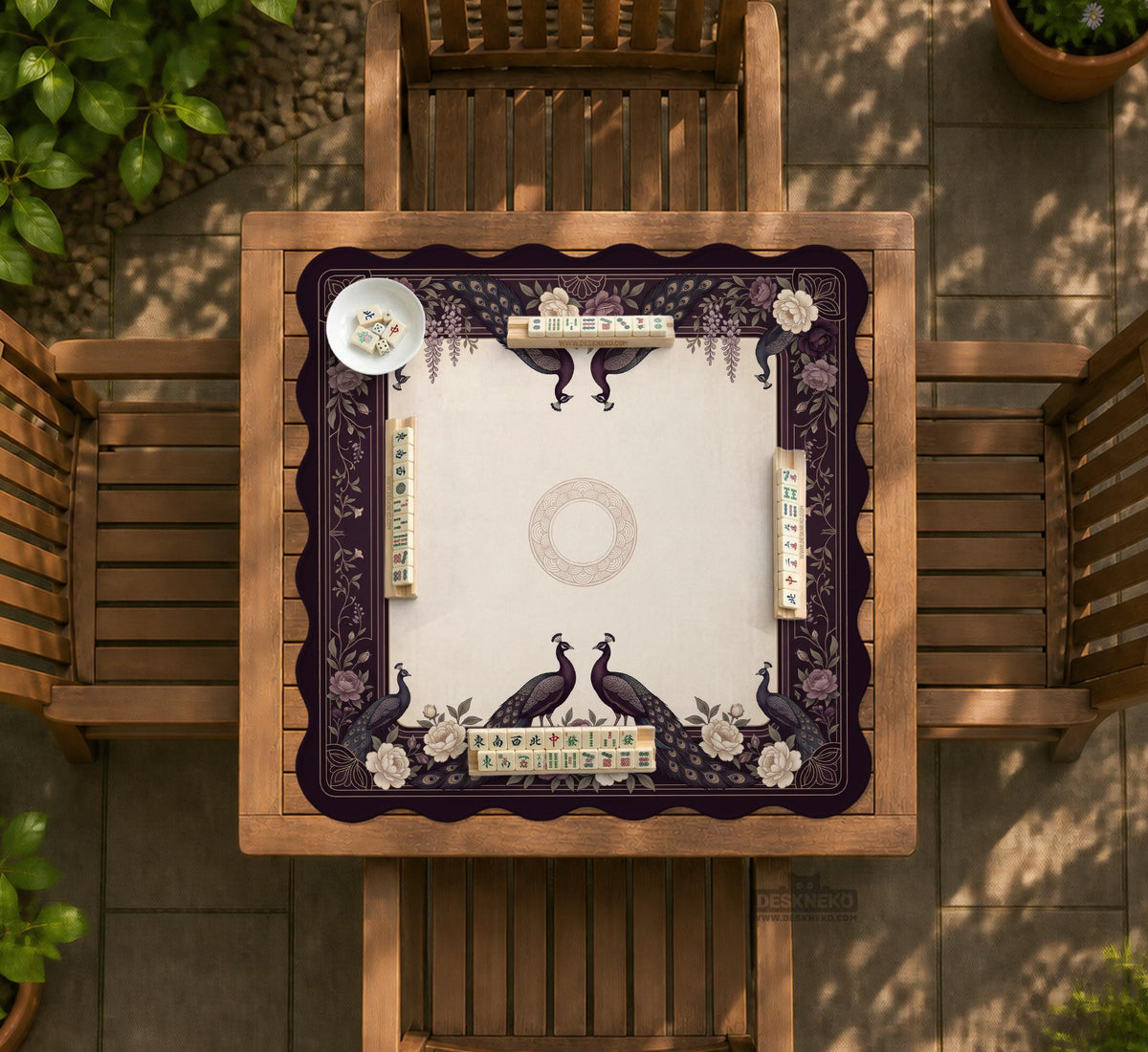 Square mahjong mat with a dark plum border, ivory floral pattern, muted sage leaves, and a decorative peacock garden design.