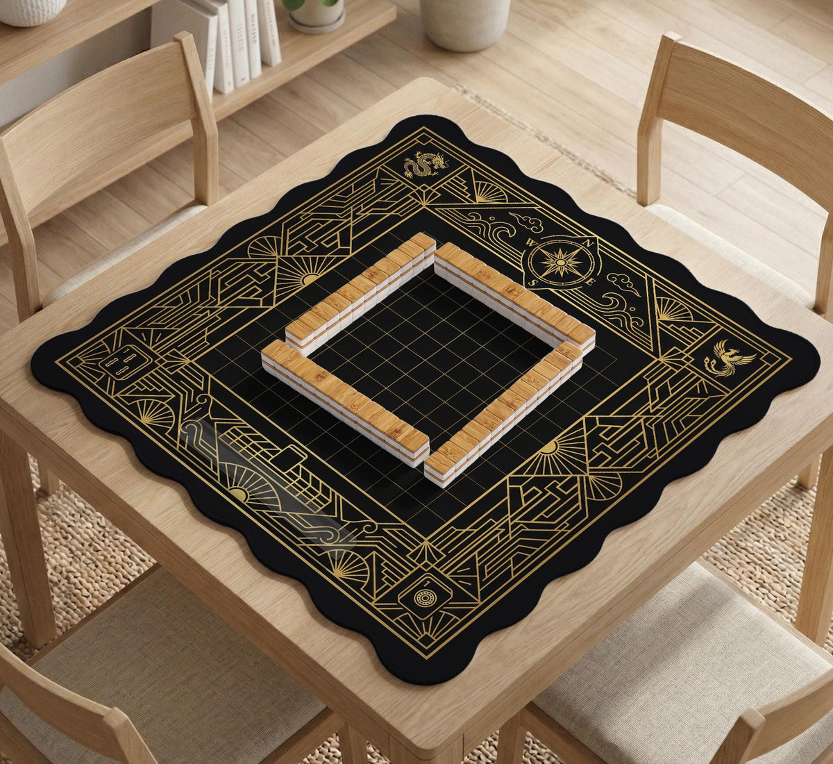 Black and gold square mahjong mat with a scalloped edge, geometric border, thin line details, fan motifs, and dragon and phoenix accents around an open center.