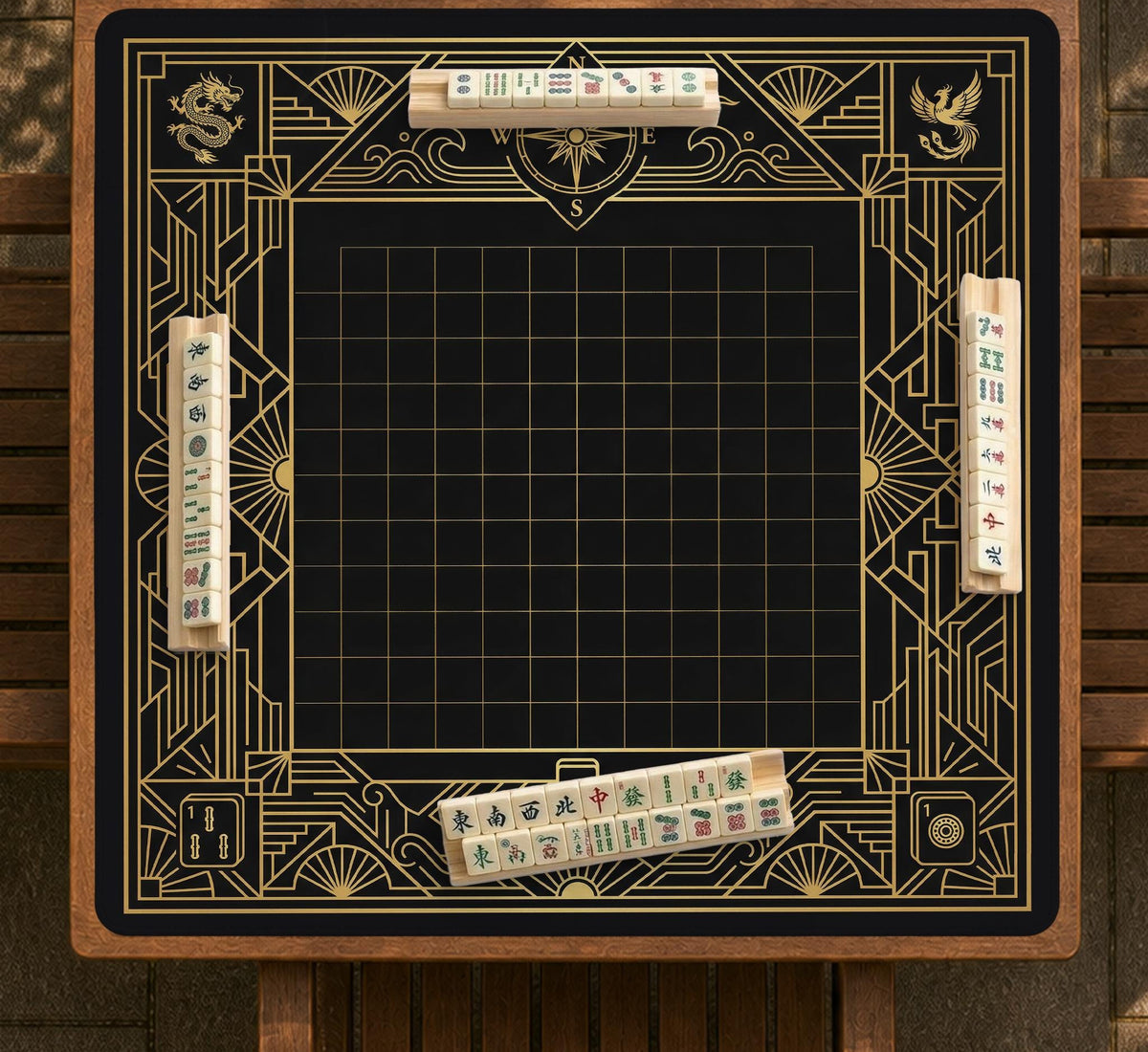 Black and gold square mahjong mat with a scalloped edge, geometric border, thin line details, fan motifs, and dragon and phoenix accents around an open center.