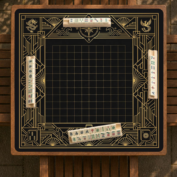 Black and gold square mahjong mat with a scalloped edge, geometric border, thin line details, fan motifs, and dragon and phoenix accents around an open center.
