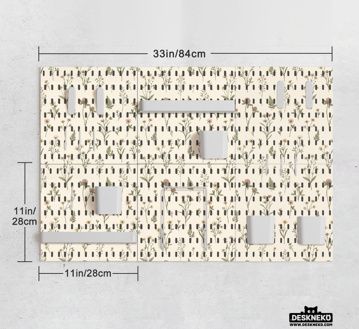 Cream pegboard wall organizer with small floral print, sage green stems, black slot layout, shelves, hooks, clips, and containers.