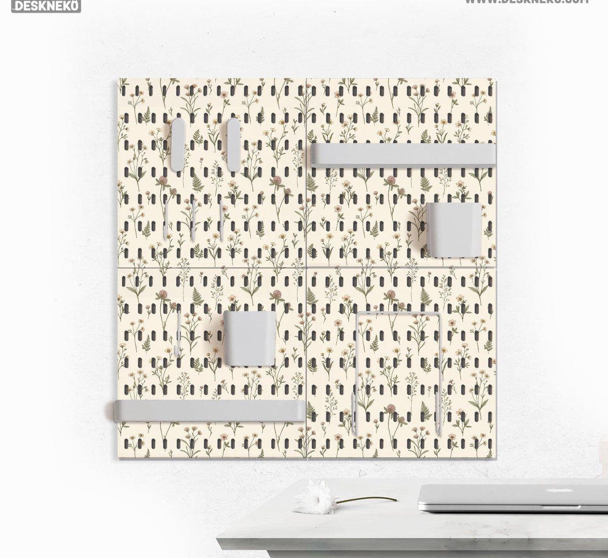 Cream pegboard wall organizer with small floral print, sage green stems, black slot layout, shelves, hooks, clips, and containers.