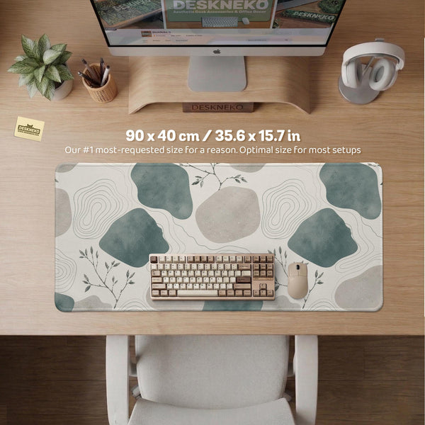 A desk mat with sage green abstract blocks, cream space, gray stone-like shapes, fine topographic contour lines, and small branch details.