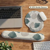 A desk mat with sage green abstract blocks, cream space, gray stone-like shapes, fine topographic contour lines, and small branch details.